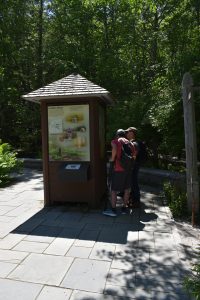 Two people standing at the information booth outside of the Acadia National Park Nature Center.