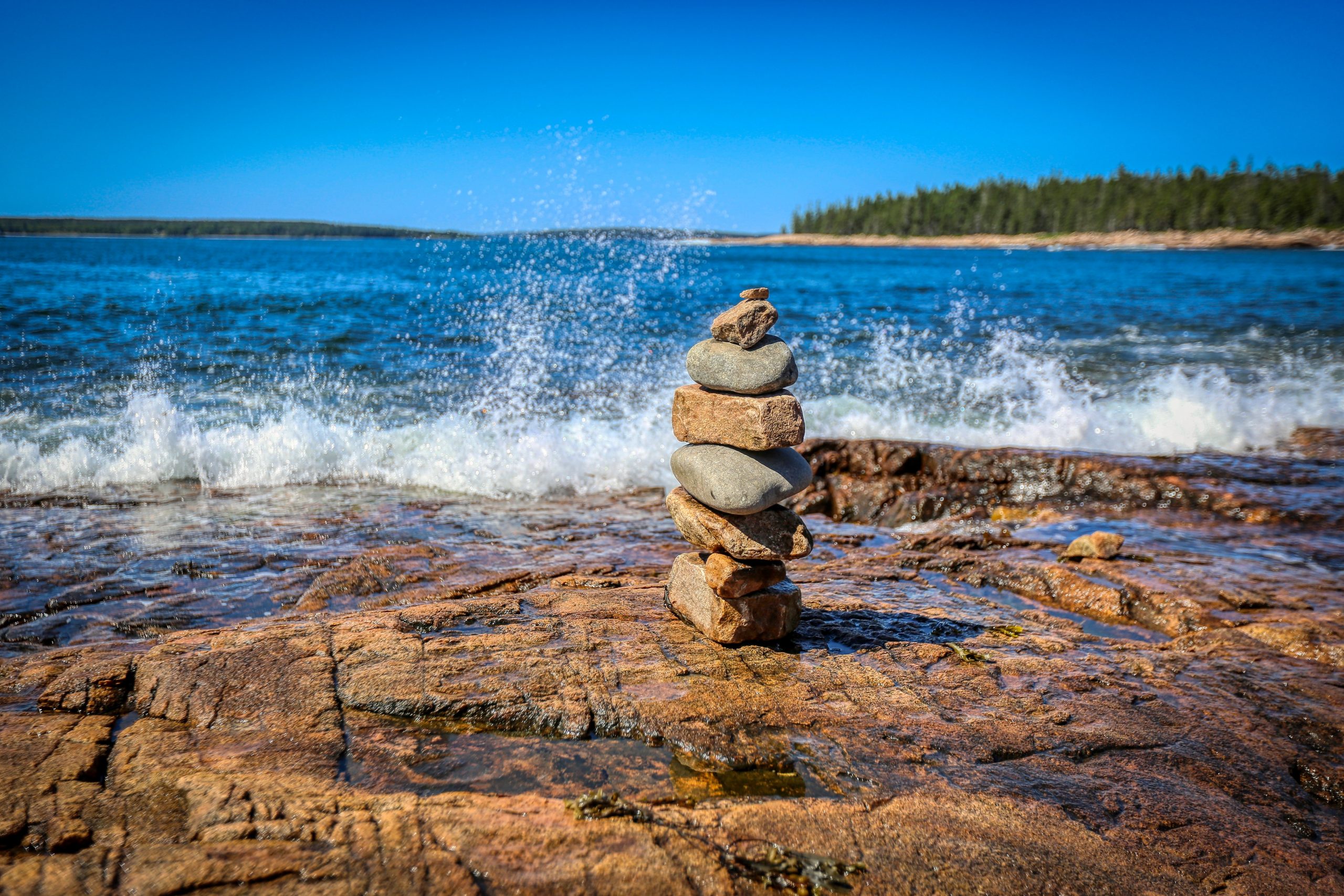 Stack of rocks with crashing wave in the background.